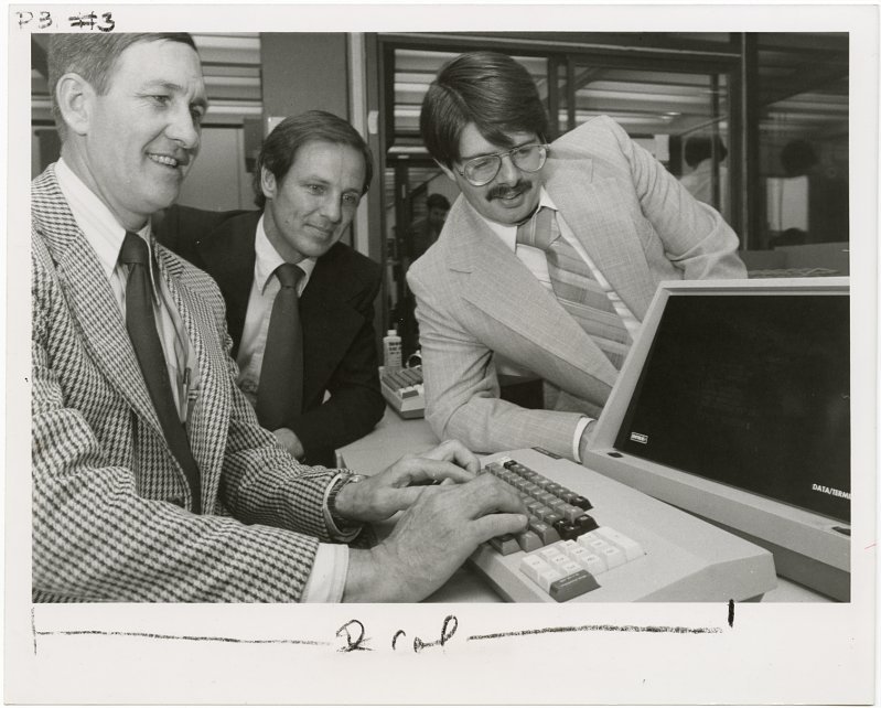 Black and white photograph of three men looking at a computer; circa 1980s; from the Smithsonian Institution Archives.